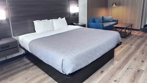 A modern hotel room with a large bed, a bedside table, a desk, a chair, and a wall-mounted light fixture. - Quality Inn Spearfish I-90 (Spearfish)