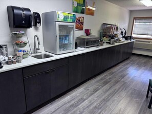 Una cocina con un lavamanos, un refrigerador y una cafetera.