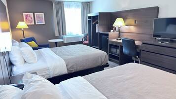 A hotel room with two beds, a desk with a computer, a TV, and a chair.