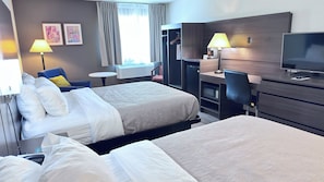 A hotel room with two beds, a desk with a computer, a TV, and a chair.