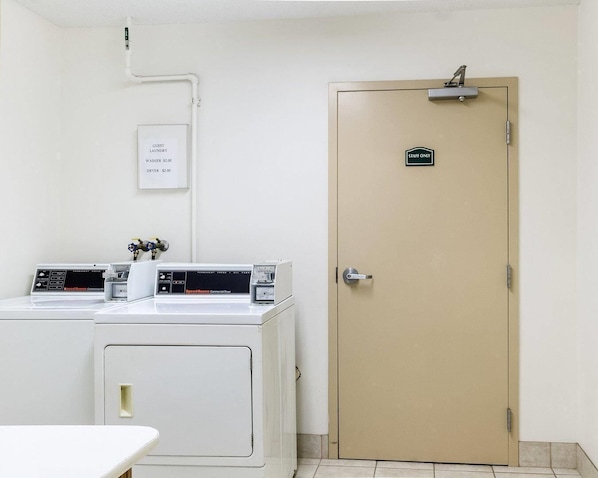 A laundry room with two washing machines, a dryer, and a staff-only door.