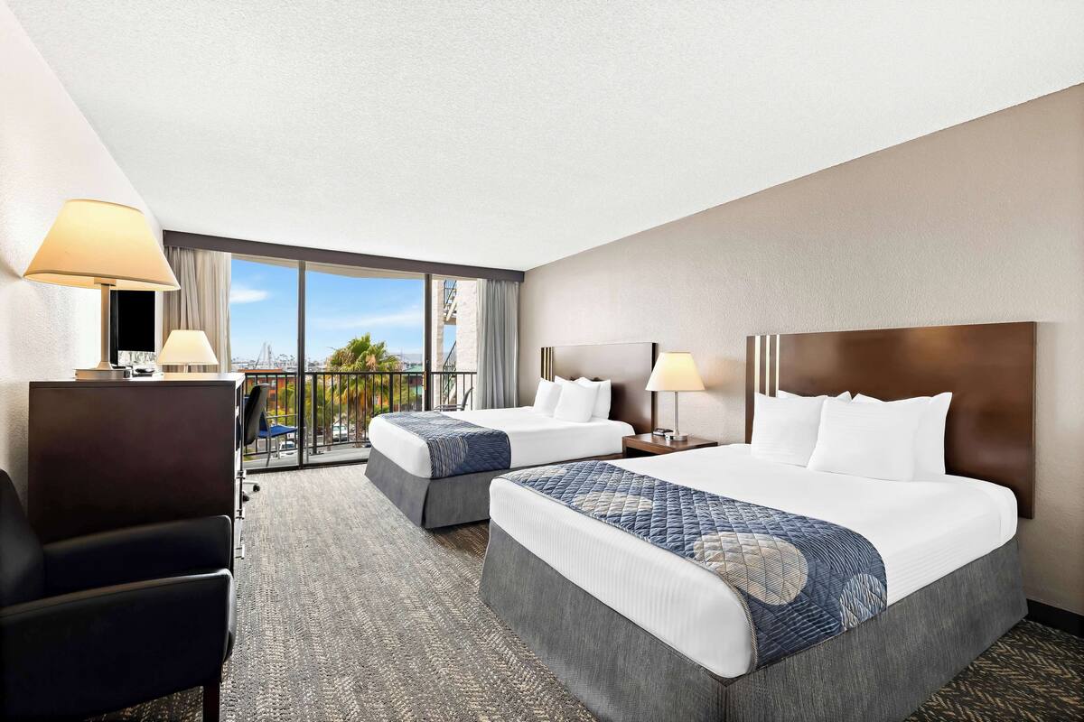A hotel room with two beds, a desk, and a chair.