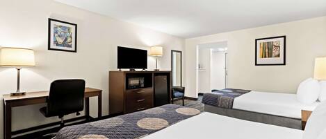 Una habitación de hotel con dos camas, un escritorio con silla, televisor y cómoda.