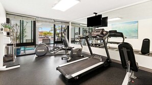 Un gimnasio con cinta de correr, elíptica y máquinas de pesas.