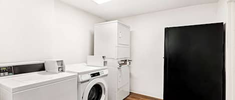 A laundry room with a washing machine, dryer, and stacked cabinets.