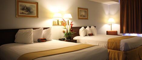 A hotel room with two beds, a nightstand with lamps, a painting, and a window with curtains.