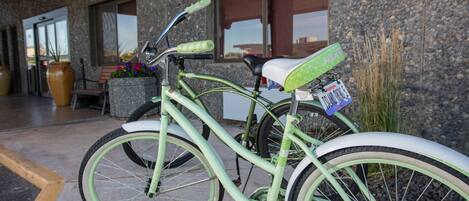 Un vélo vert est garé devant un immeuble à la façade en pierre et aux grandes fenêtres.
