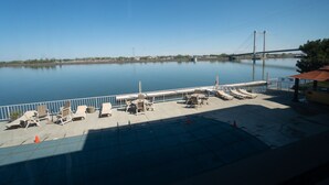 A calm waterfront area with lounge chairs and a view of a bridge. - Clover Island Inn (Kennewick)