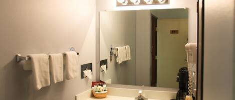 Baño con lavamanos, espejo, toallero y cafetera.