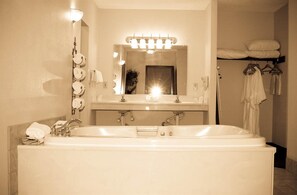 A bathroom with a large bathtub, a sink, a mirror, and a towel rack.