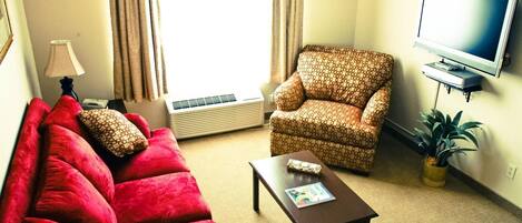 A living room with a red sofa, patterned armchair, and a coffee table.