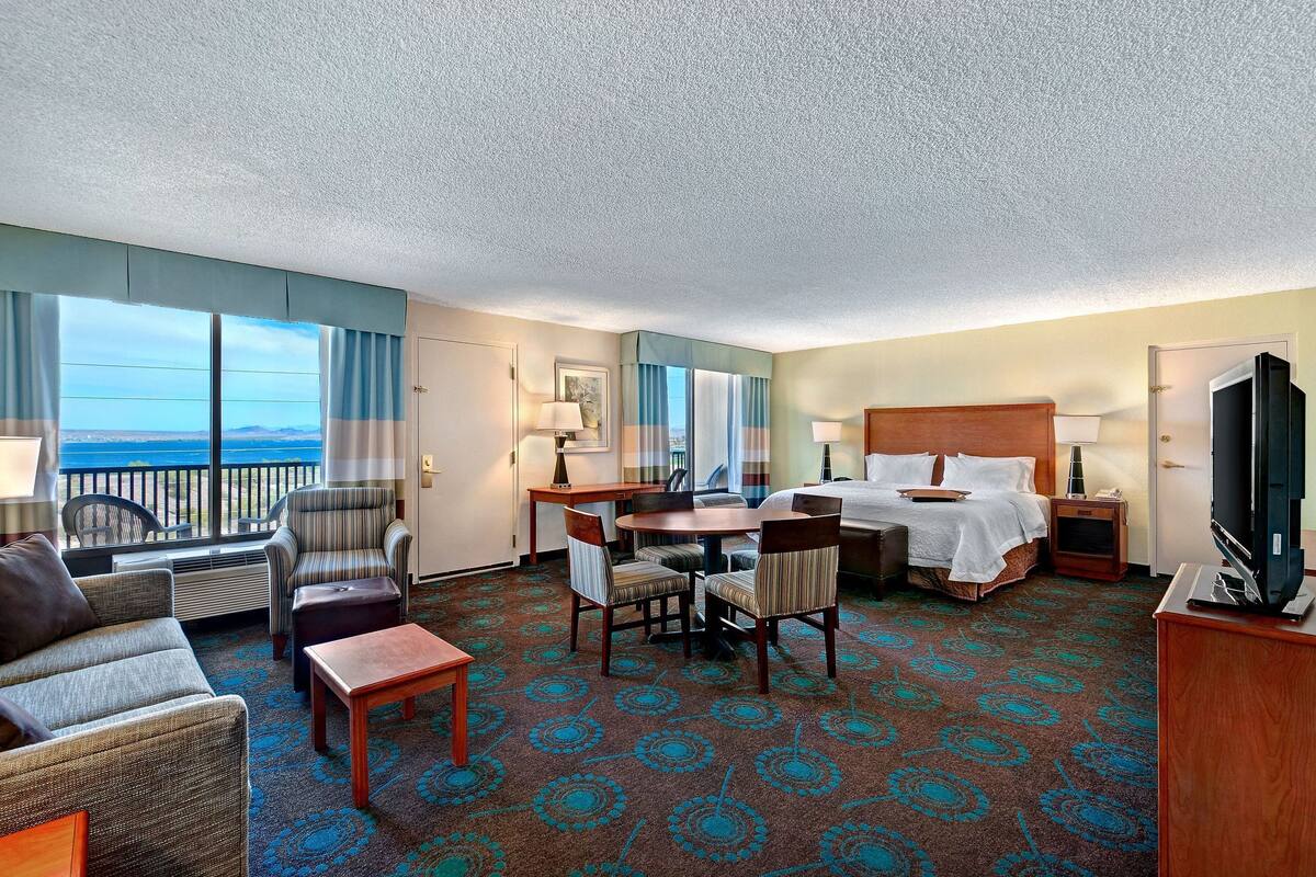 Une chambre d’hôtel équipée d’un lit, d’un bureau, d’une chaise, d’un canapé et d’une télévision.