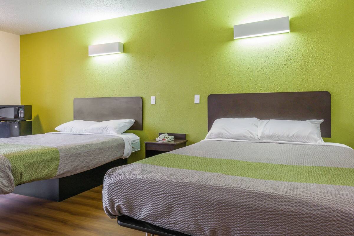 A hotel room with two beds, a microwave, and a small table.