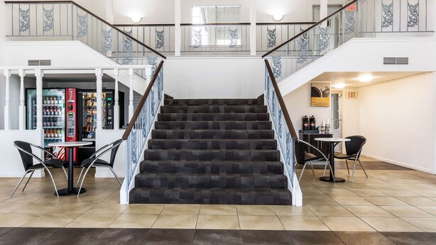 A staircase with a dark carpet and white balusters, leading to a second floor. - Motel 6 Alexandria, LA - South (Alexandria)