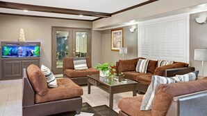 A modern living room with brown sofas, a glass coffee table, and a television. - Days Inn by Wyndham West Covina (West Covina)