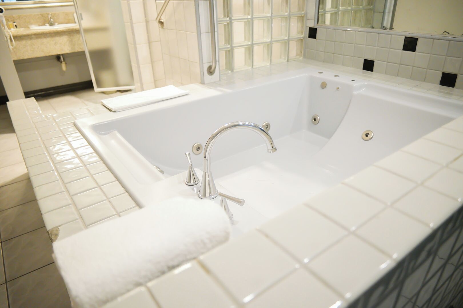 A modern bathroom with a white bathtub, a single faucet, and a tiled floor.