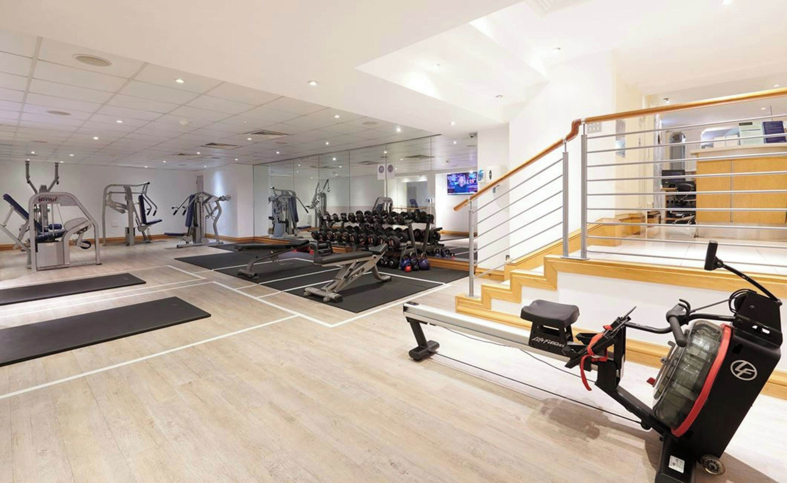 Une salle de sport équipée de matériel d’exercice, d’un banc de musculation et d’un escalier.