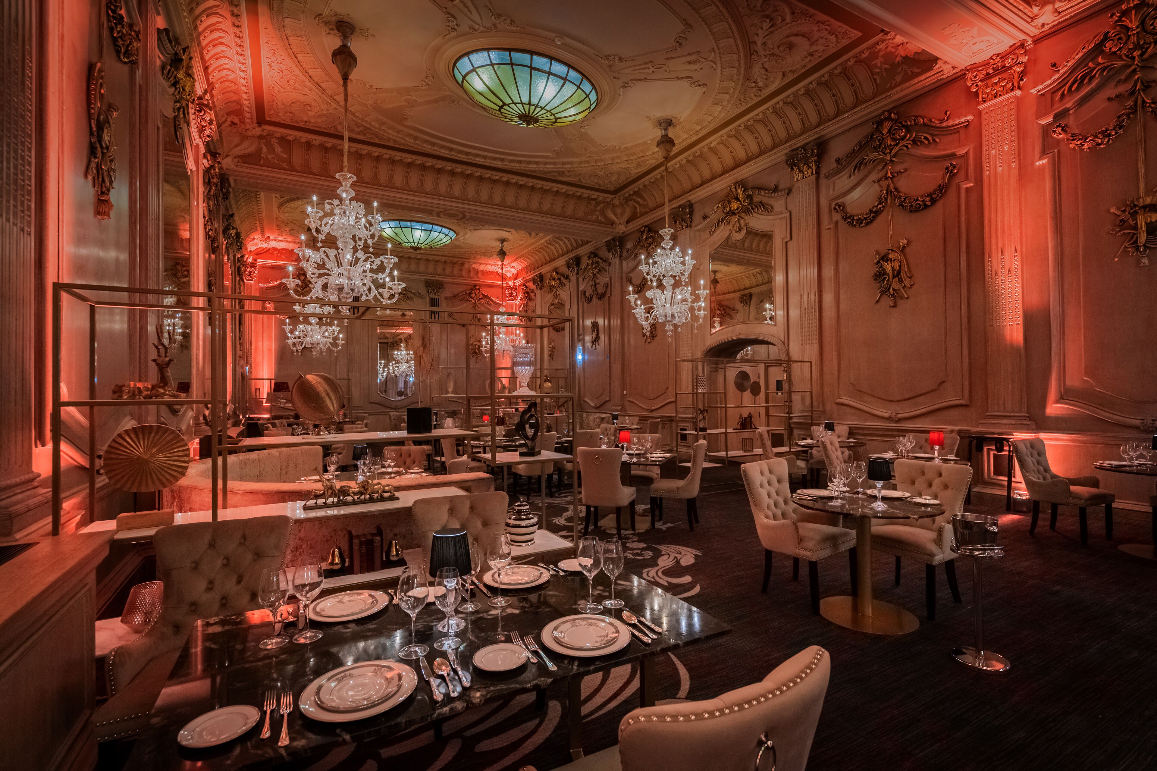 Un comedor lujoso con candelabros ornamentados, elegantes vajillas y decoración clásica.