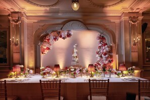 A formal dining room with a long table set for a meal, elegant chairs, and a decorative archway with balloons. - The Dilly (London)