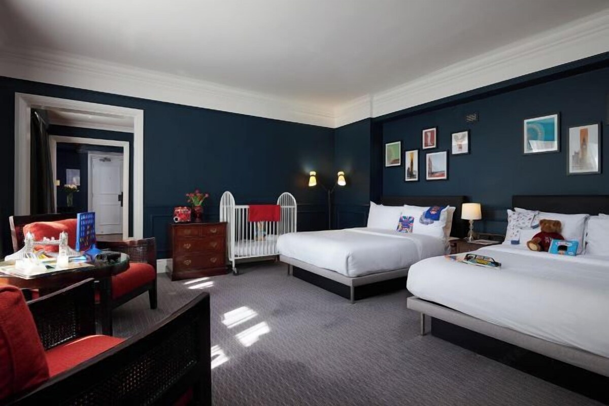 A hotel room with two beds, a desk, and a chair.