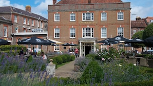 A historic building with a sign reading "Crown Hotel," featuring a traditional brick facade, multiple windows, and outdoor seating with umbrellas. - Crown Hotel (Blandford Forum)