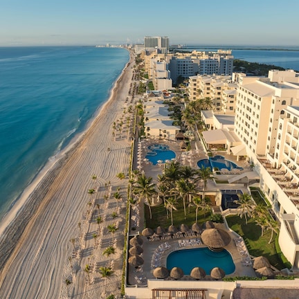 A resort with a beachfront, multiple swimming pools, and high-rise buildings.