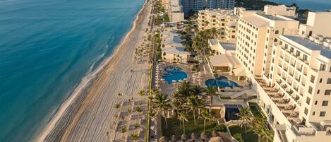A resort with a beachfront, multiple swimming pools, and high-rise buildings.