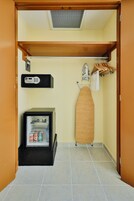 Habitación pequeña con refrigerador, microondas y tabla de planchar de madera.