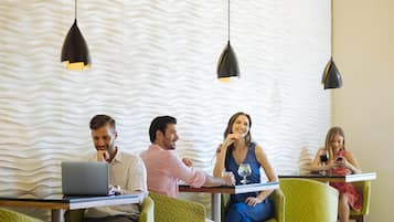 Un interior moderno con un patrón de pared ondulado, sillas tapizadas en verde e iluminación colgante.