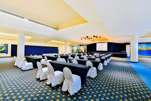 A conference room with rows of tables, chairs, and a stage. - Occidental Tucancún All Inclusive (Cancun)