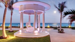 A gazebo with a circular roof, surrounded by palm trees and a view of the ocean. - Occidental Tucancún All Inclusive (Cancun)