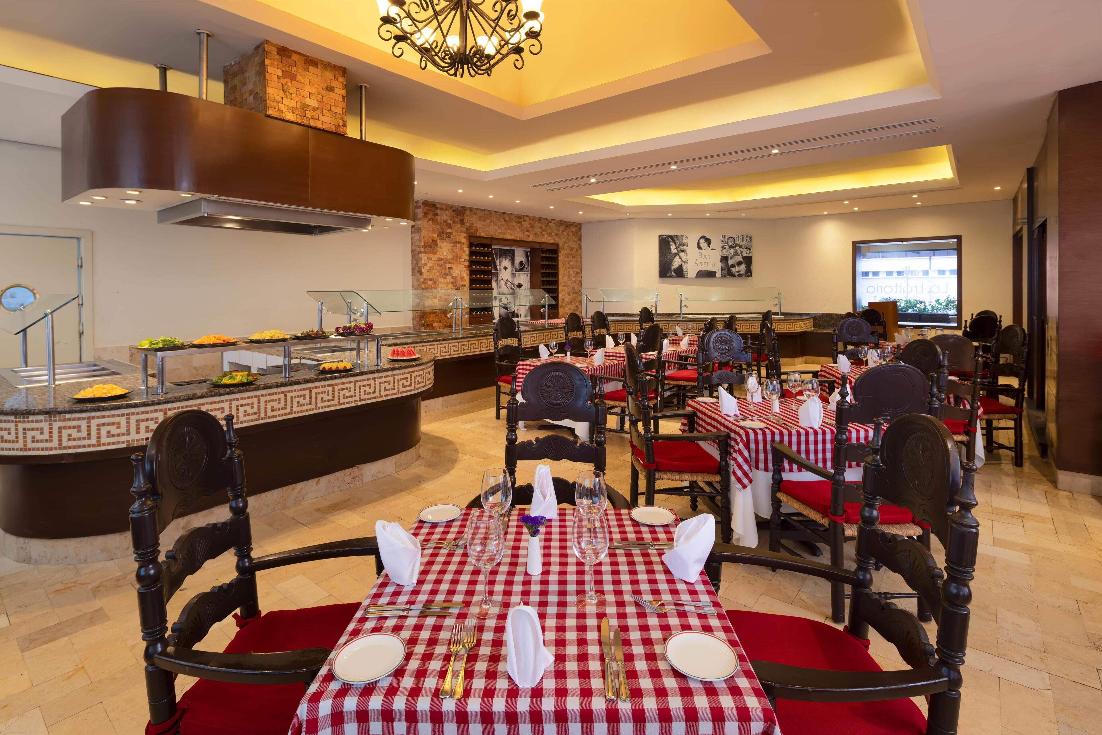 Un restaurant avec des nappes à carreaux, des chaises rembourrées de couleur rouge et un espace buffet proposant une variété de plats.