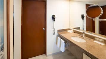 Un baño con dos lavamanos, un espejo grande y un secador de pelo fijado a la pared.