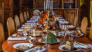 A formal dining room with a long table set for a meal, surrounded by bookshelves. - Demeures de campagne Domaine de Maffliers – Novotel (Maffliers)