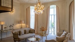 A spacious living room with a sofa, armchairs, a coffee table, and a chandelier. - Demeures de campagne Domaine de Maffliers – Novotel (Maffliers)
