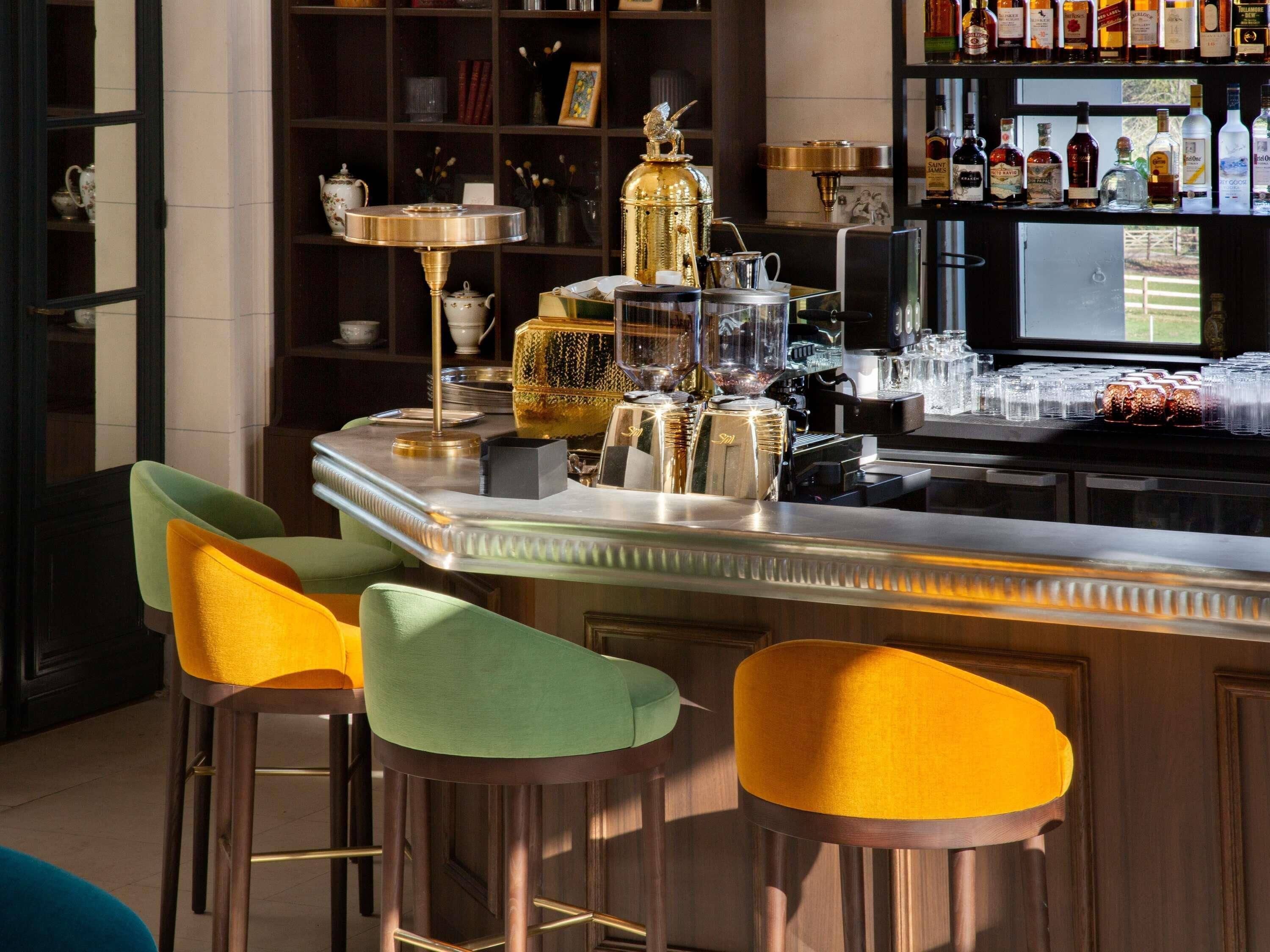 A bar area with stools, a coffee machine, and a shelf with bottles.
