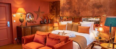 A hotel room with a large bed, a sofa, a small table, and a chair.