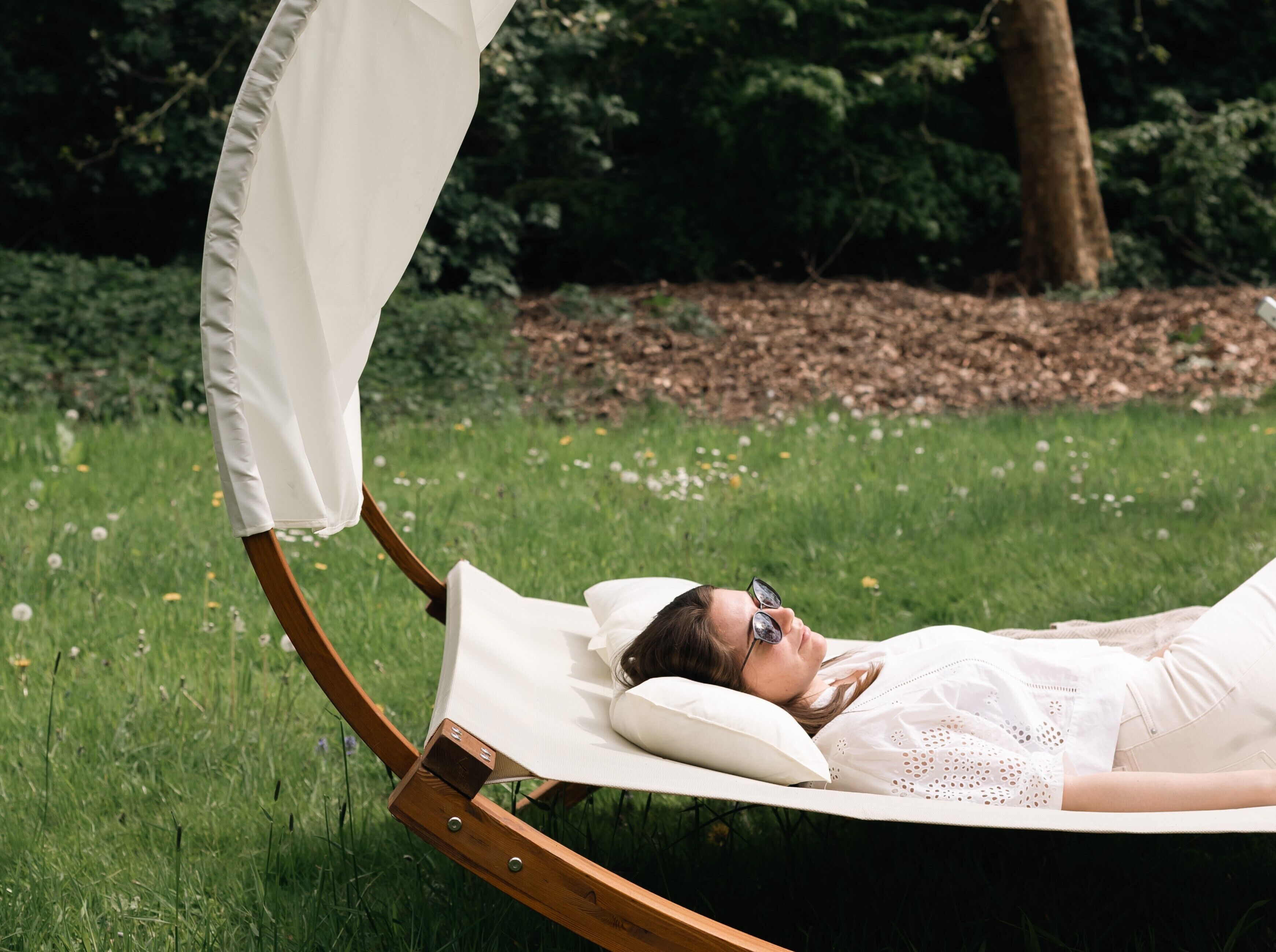 A person lying on a reclining chair outdoors with a canopy.