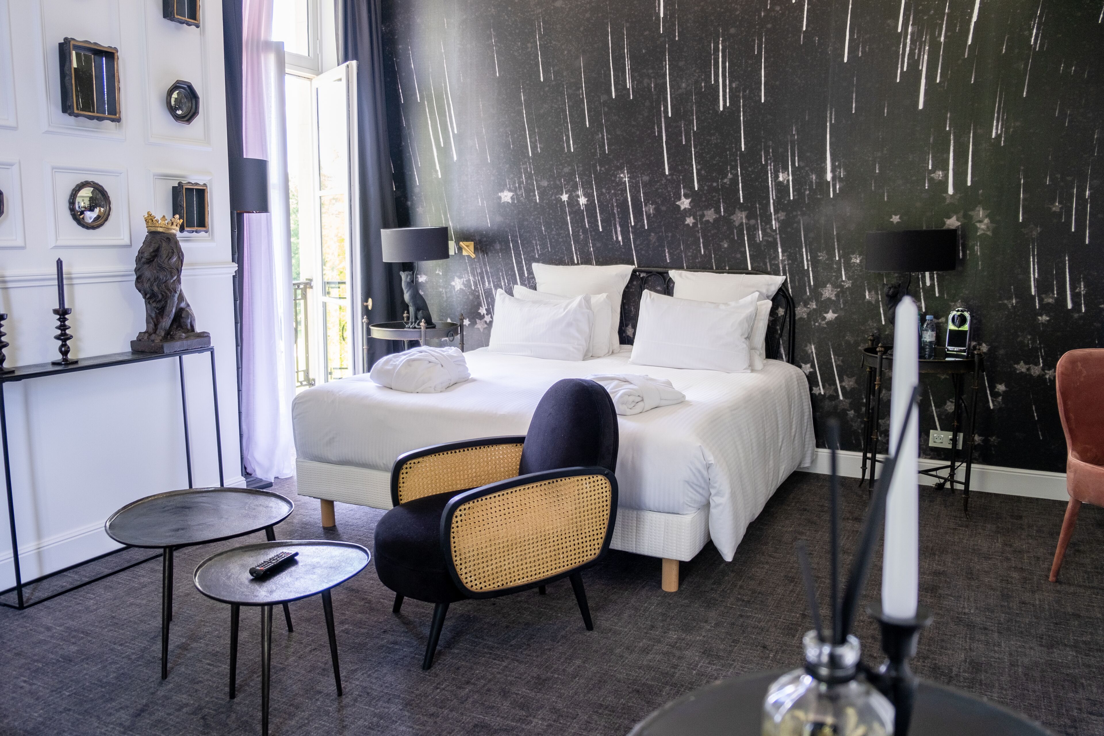 Una habitación de hotel moderna con una cama grande, una mesita pequeña, una silla y un adorno en la pared.