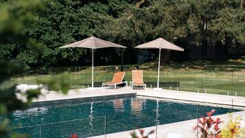 Una piscina techada, una piscina al aire libre de temporada, sombrillas