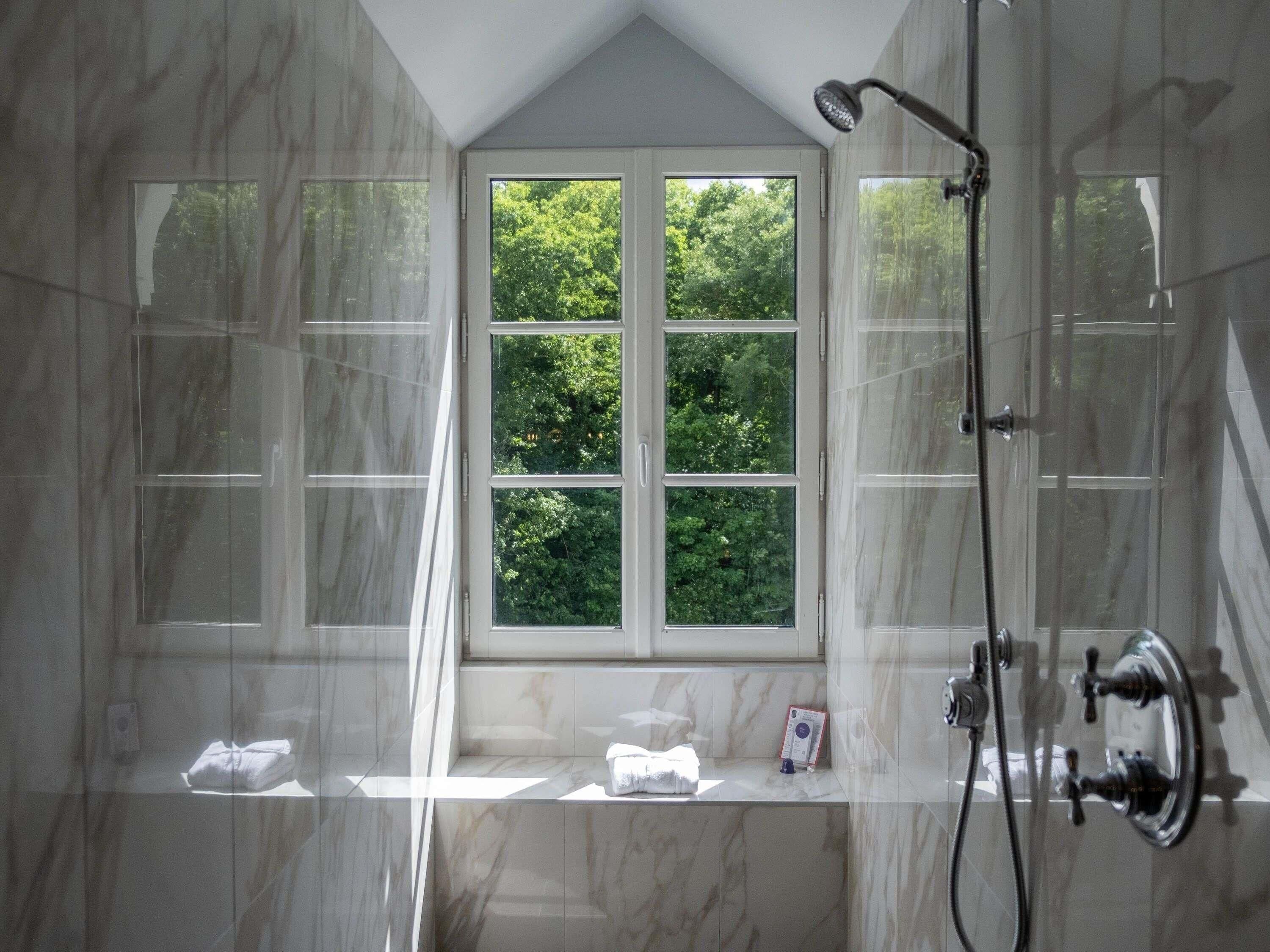 A bathroom with a large window, a shower, and a towel rack.