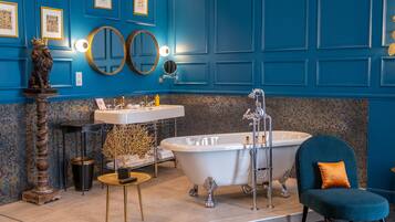 Bathroom features a bathtub, pedestal sink, and round mirror with overhead lighting.