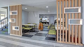 A modern interior with a checkered floor, a dining area with green chairs, and a kitchen in the background. - Quality Inn Pierre - Fort Pierre (Pierre)