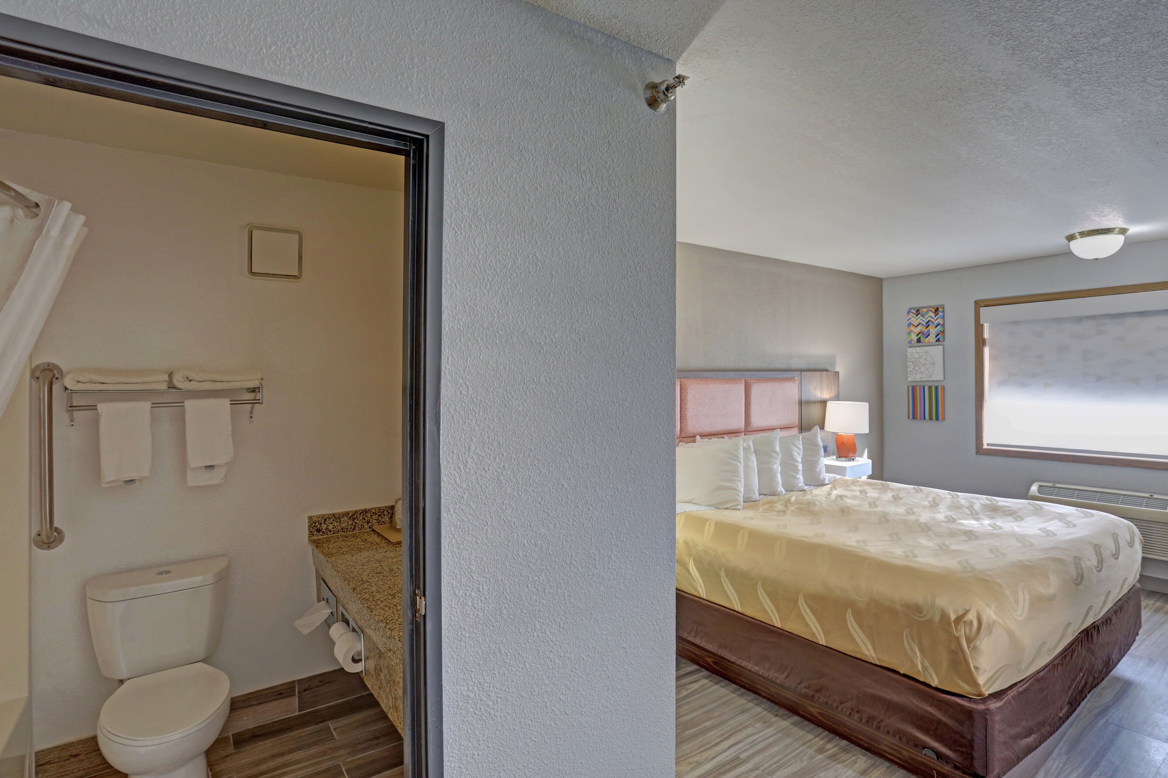 Una habitación de hotel con baño, cama y ventana.