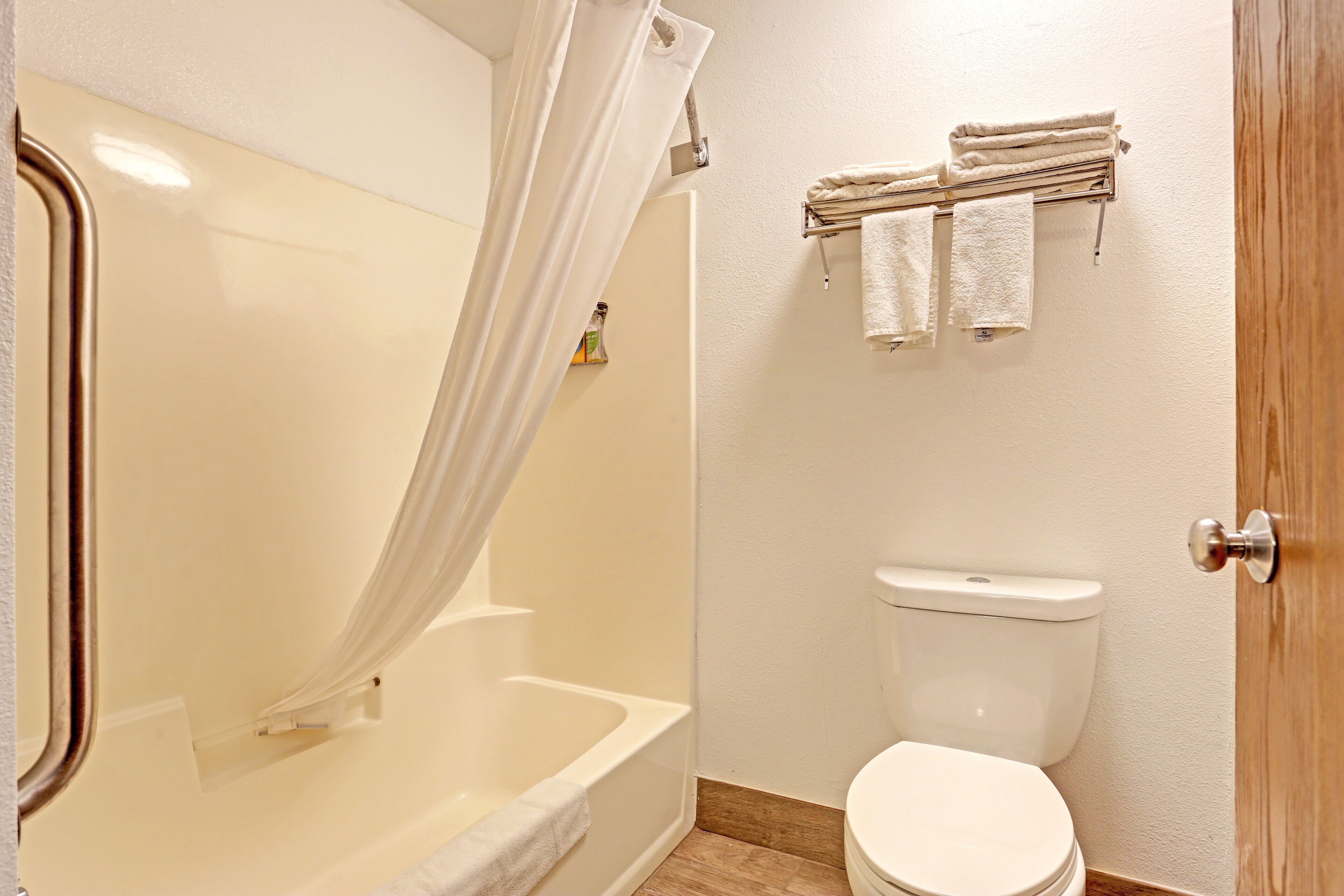 A bathroom with a bathtub, toilet, and a towel rack with towels.
