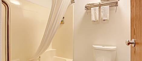 A bathroom with a bathtub, toilet, and a towel rack with towels.