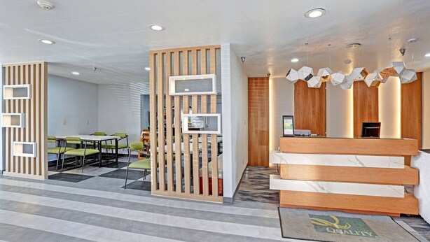 A reception area with a wooden desk, a seating area with green chairs, and a patterned floor. - Quality Inn Pierre - Fort Pierre (Pierre)