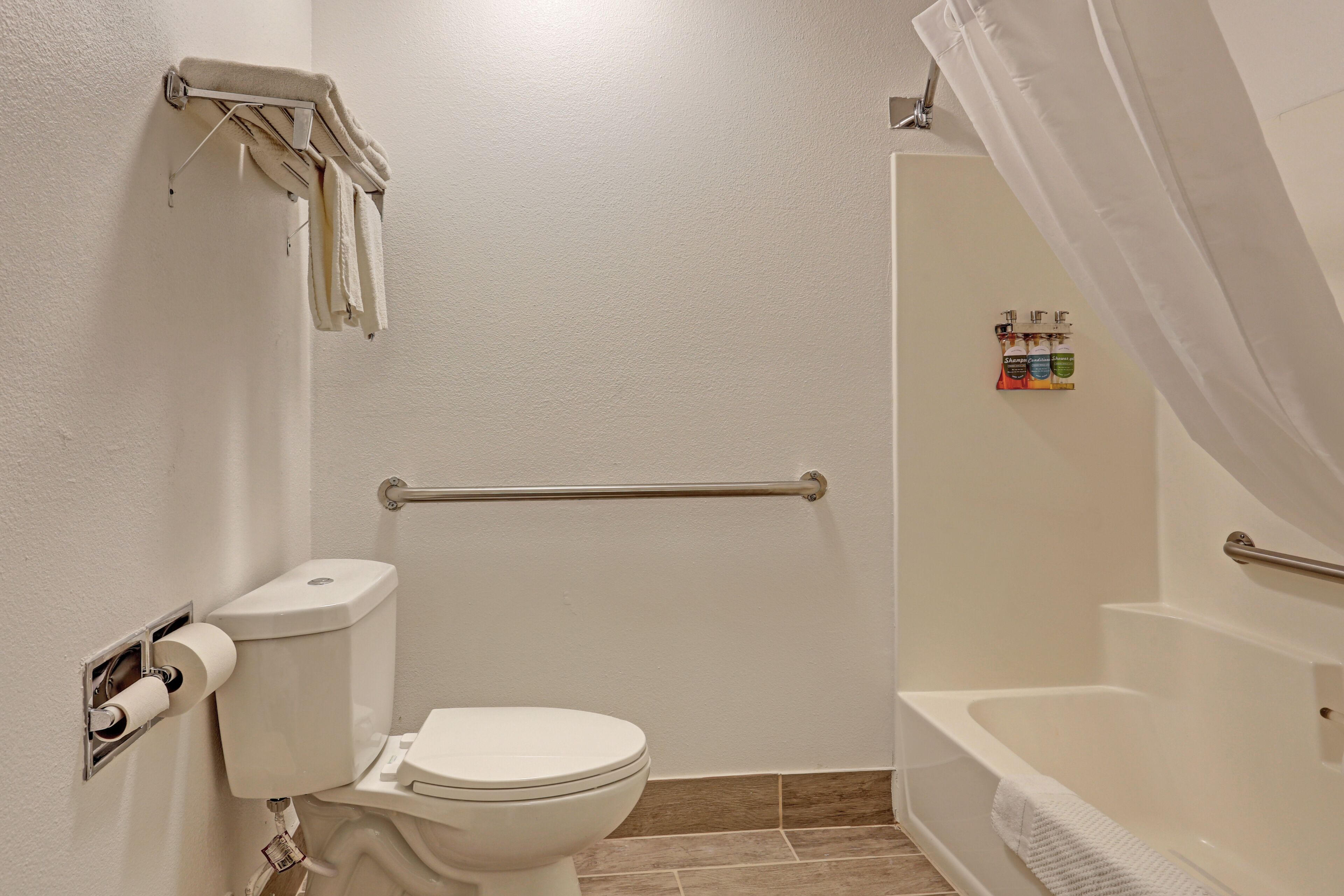 A bathroom with a toilet, a shower with a curtain, and a towel rack.