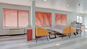A modern waiting area with large windows, a central table, and comfortable seating. - Quality Inn Pierre - Fort Pierre (Pierre)