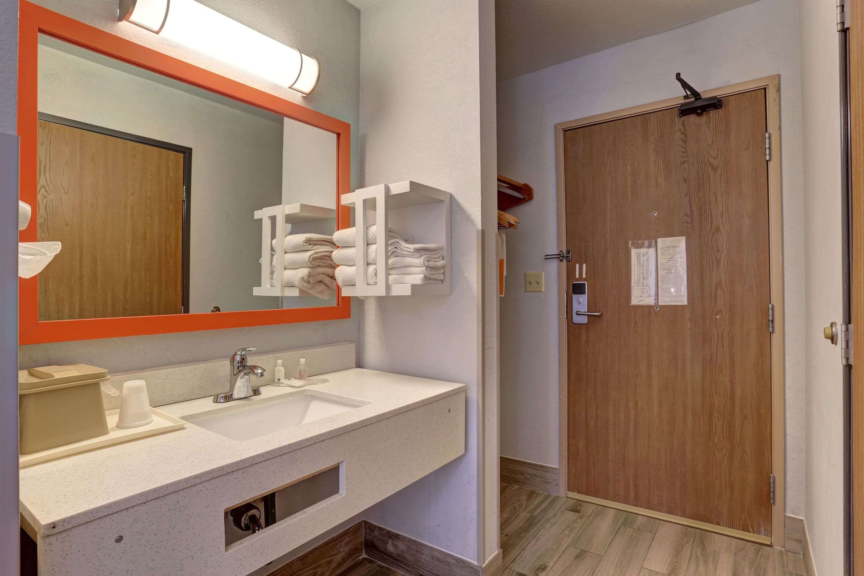 Un bagno d'albergo con uno specchio grande, due lavabi e una porta in legno.